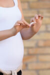 Zwangere vrouw die een sigaret doorbreekt